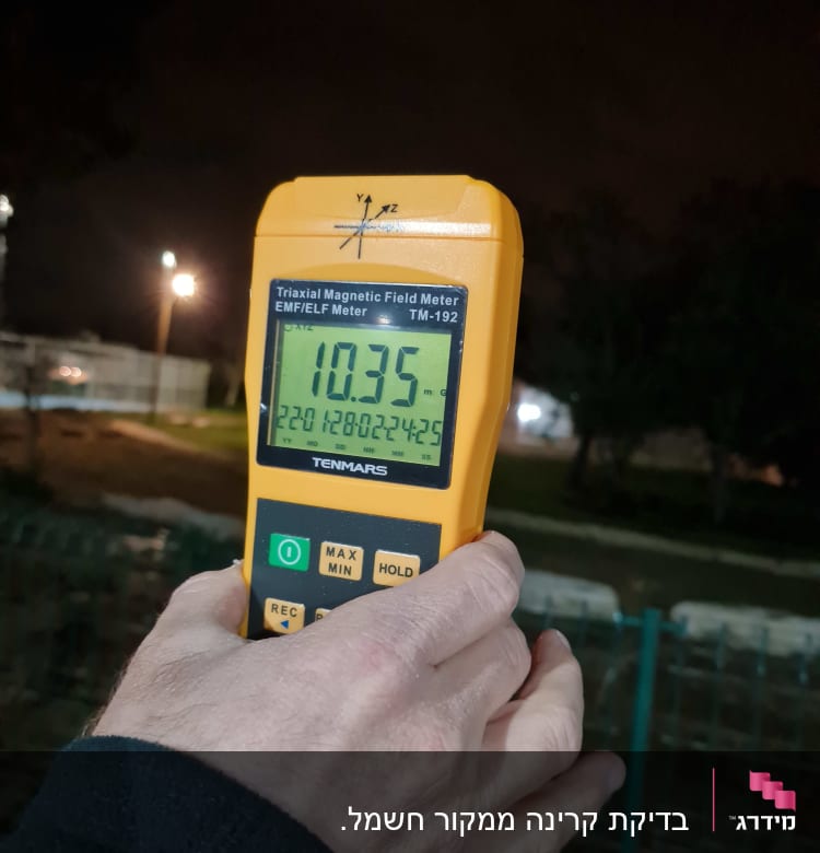 מד קרינה מגנטית מוחזק ביד בלילה